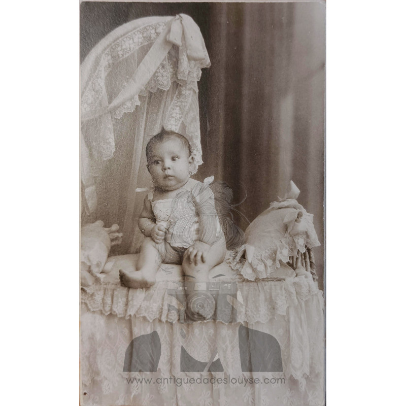 NIÑA EN PEQUENA CAMA RODEADA DE ENCAJES